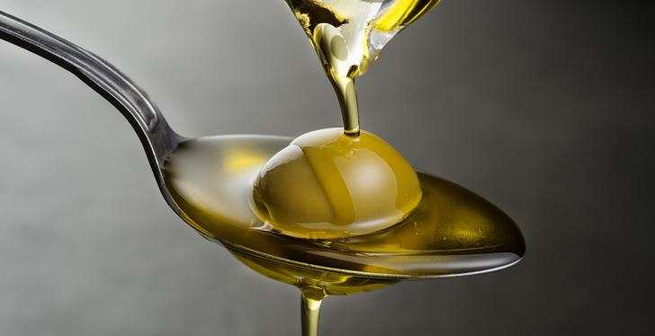 Olive oil trickling down onto a spoon with an olive on it; copyright:...