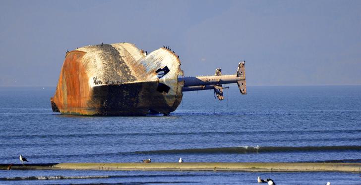 Wrecked ship lying on its side in the sea close to the shore; copyright:...