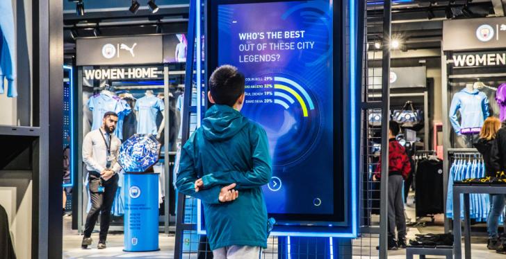 Boy standing in front of a digital screen in a sport’s store; copyright:...