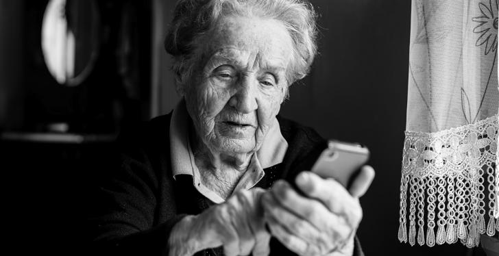 A senior woman uses a smartphone, image in black and white; copyright:...
