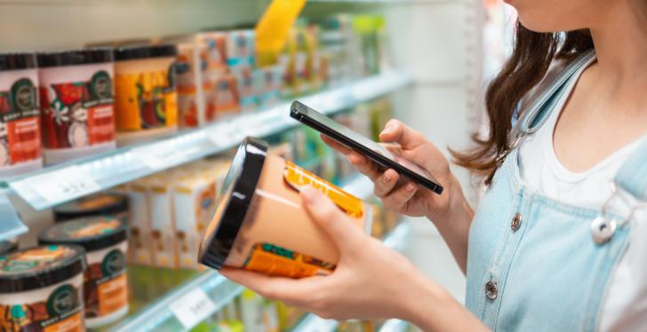 Eine Frau scannt mit dem Handy Ware im Supermarkt