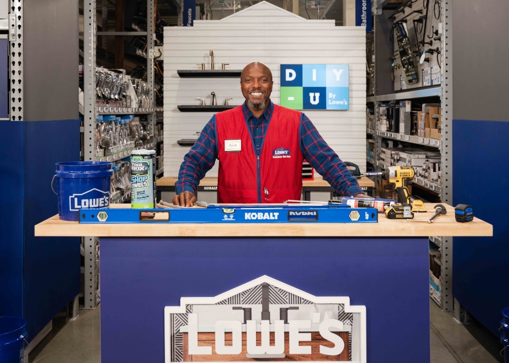 A home improvement store employee stands behind a counter and smiles for the...