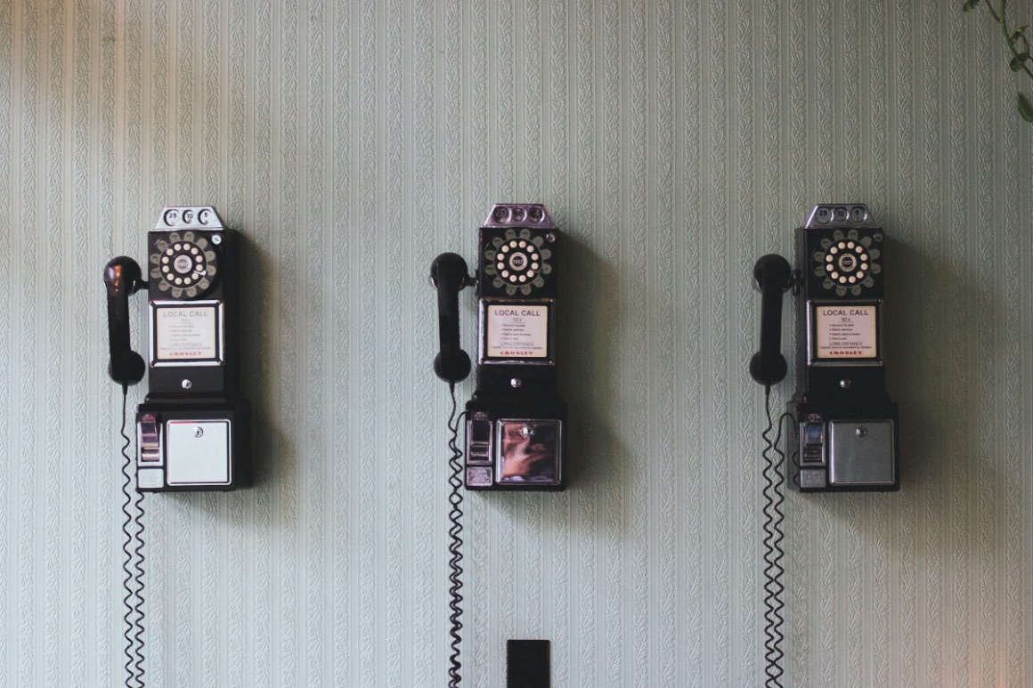 3 old telephones hanging on a wall