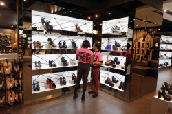 Employees arrange a display of womens footwear in the shoe department the...