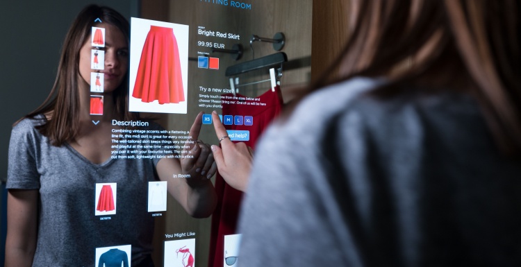 Photo: Woman using a digital touch screen in a dressing room; copyright: Detego...