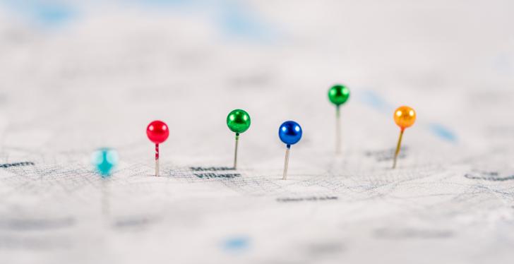 Several colored pins sticking in a paper map; copyright:...