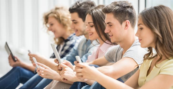 Young people sitting in a row looking at their smartphones; copyright:...