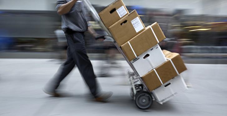Man with sack truck loaded with parcels walks through a logistics center...