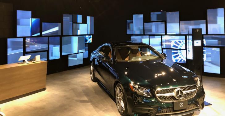 Many different digital signage screens in a showroom with a Mercedes...