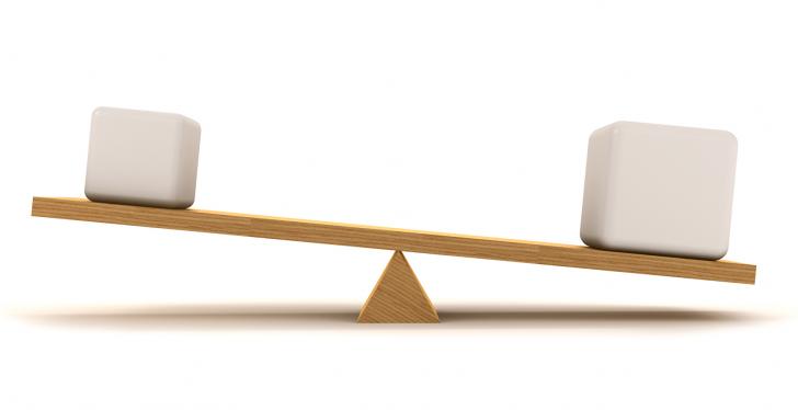 A simple wooden seesaw in imbalance with white packets on it...