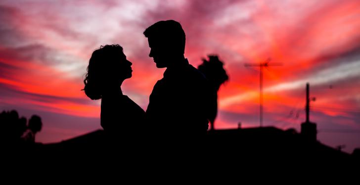 The dark silhouettes of a woman and a man in front of a red sunset; Travis...