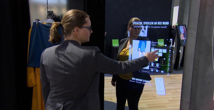 A woman operates an interactive mirror in a changing room...