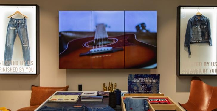A digital screen with photo of a guitar in a jeans store...