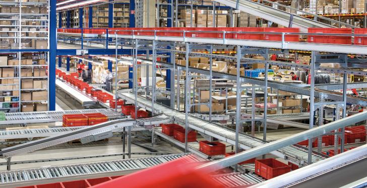 A huge warehouse where many red crates and cardboard boxes are transported via...