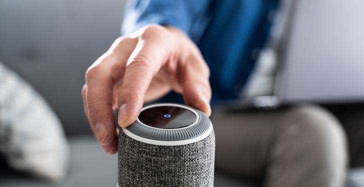 A hand is touching a Smart Speaker