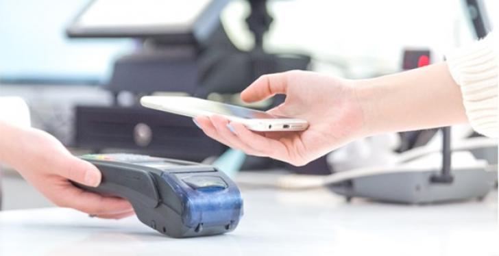 a smartphone is placed over an NFC reader to make a payment...