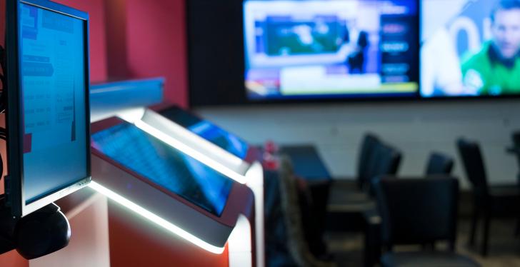 Multiple screens and tables with chairs in a large room...