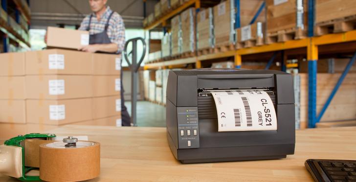 A label printer stands on a table in a warehouse