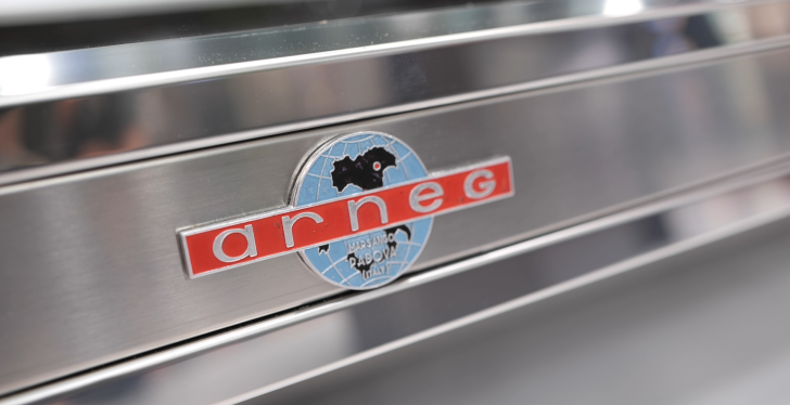 Image: Silver metal panel with the logo of the company Arneg....