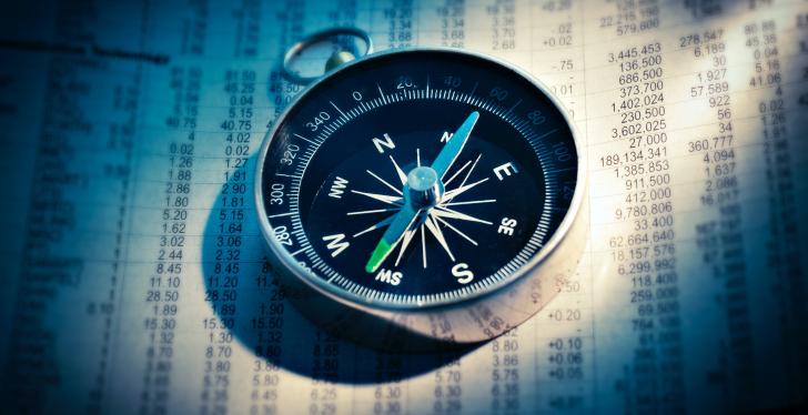 A compass lies on a page with numbers and balances