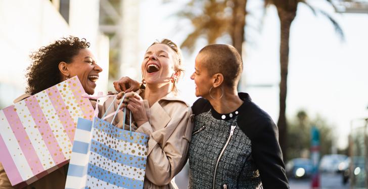 Three women laughing with shopping bags in their hands...