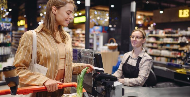 A woman stands at a checkout with her shopping.