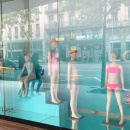 Four child mannequins in swimsuits in a shop window with blue background...