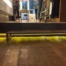 A yellow lighting provider under an edge over a wooden floor...
