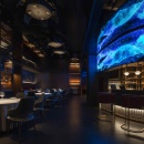 A restaurant with a blue LED screen above the bar