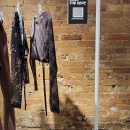 A clothes rack with few clothes and a paper sign with QR code on it in front of...