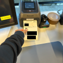 A person pulls a freshly printed shipping label from a Honeywell label printer....
