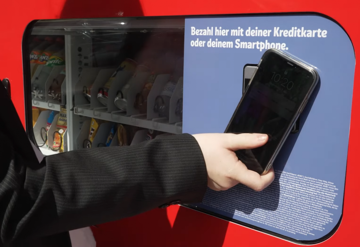A person holds a smartphone to the self-driving kiosk to pay...