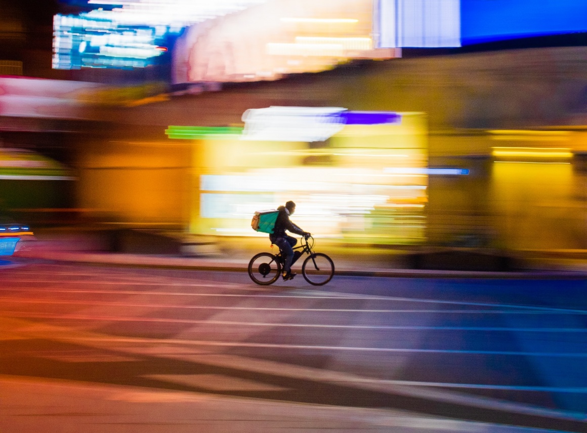 Person on a bicycle in front of a blurred city backdrop; Source: Paolo...