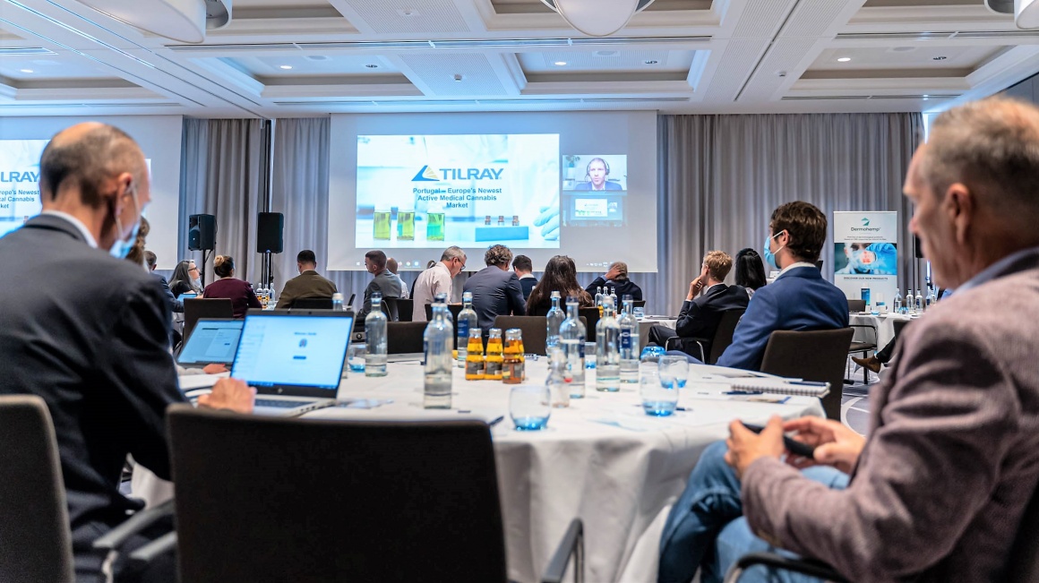 Audience members sitting at tables in a conference watching a presentation...