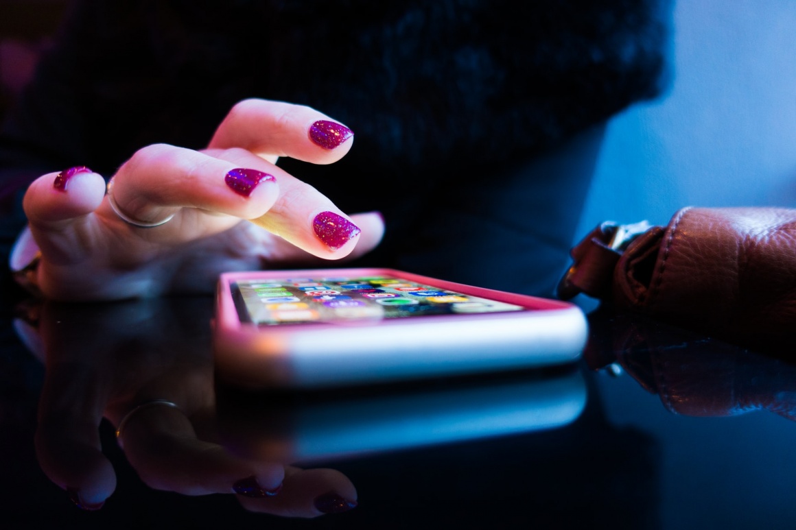 A person with colourful nails using a smartphone; Copyright: Rob...