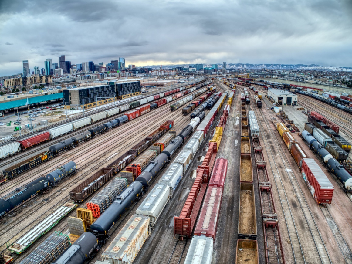 Many tracks with wagons of container trains at a big station in a city...
