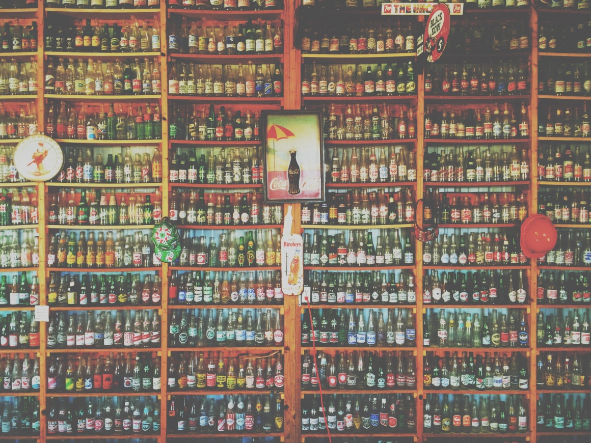 A wooden shelf in a store completely filled with bottles from top to bottom...