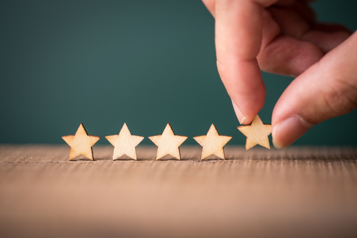 A hand placing a fifth wooden star next to four others...