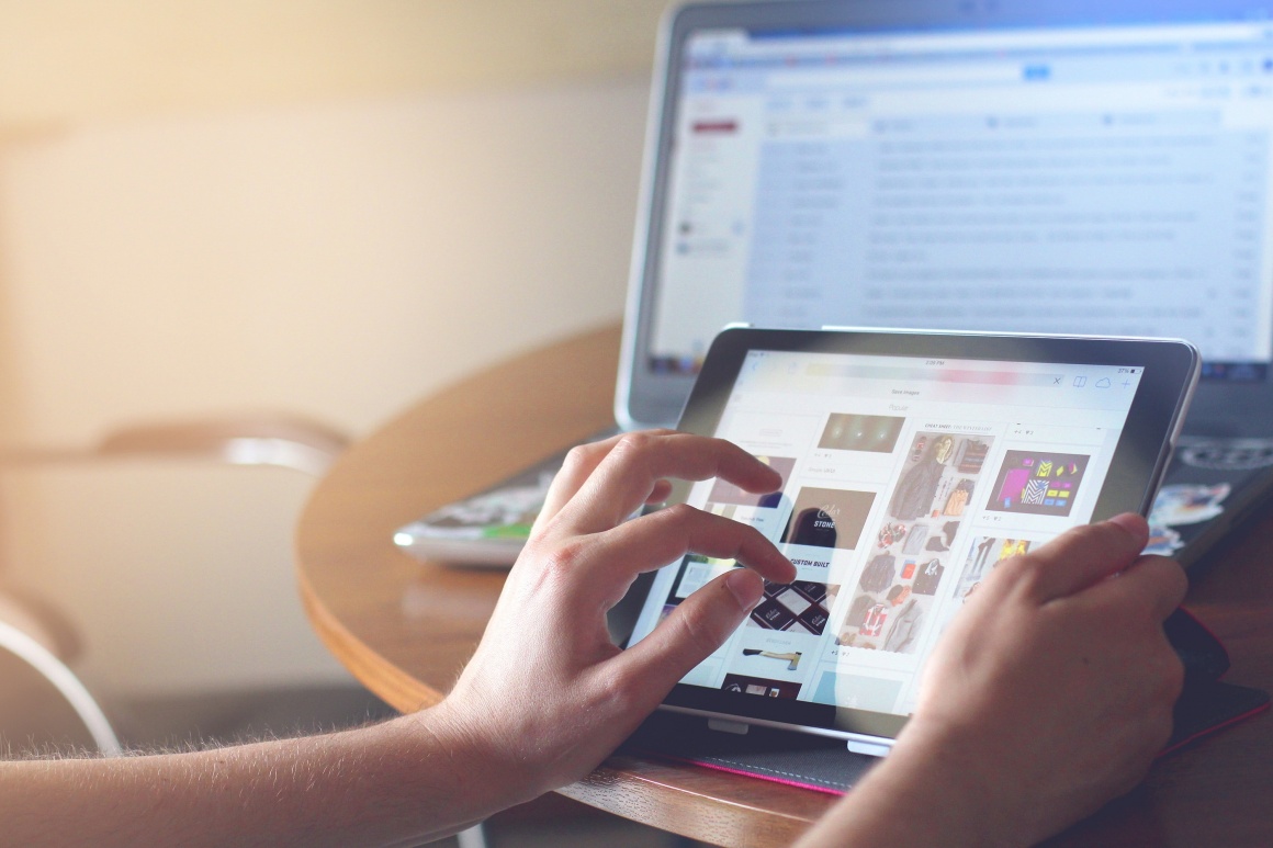 A person using a tablet in front of a notebook