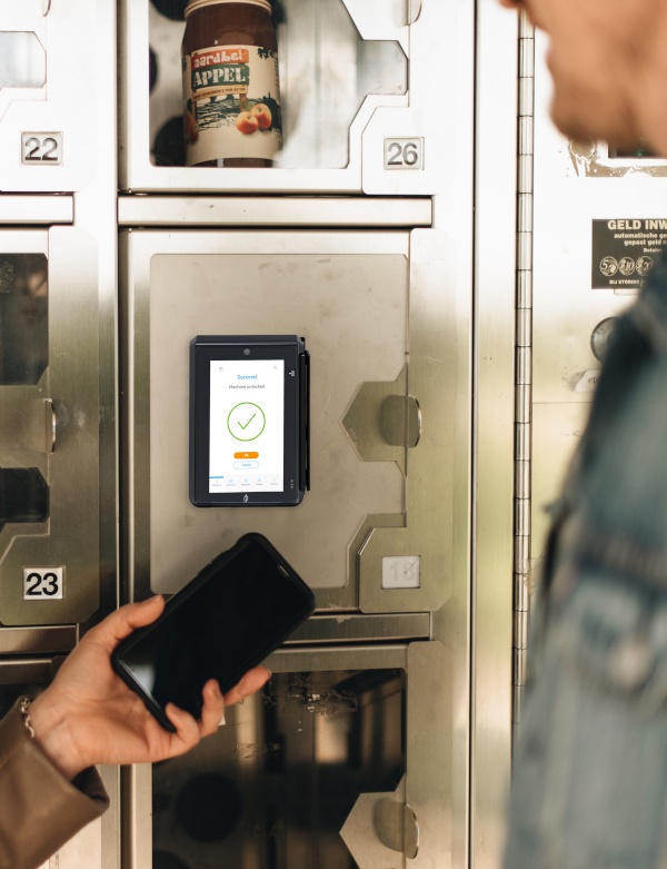 A person holds a smartphone to a payment terminal of a vending machine...