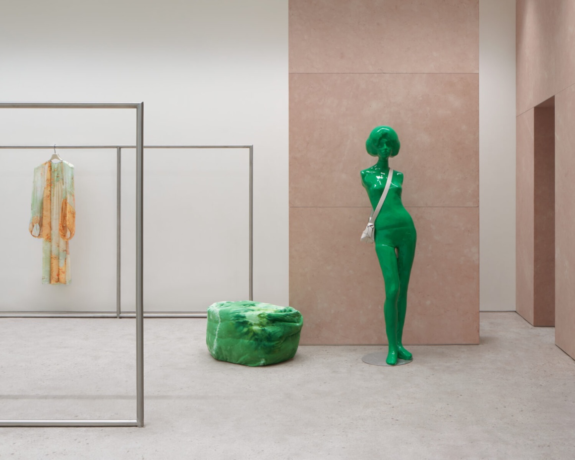 A green fashion mannequin stands next to a green lounge chair...