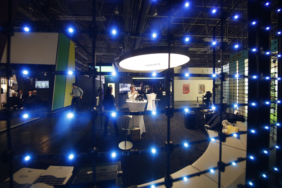 Atmospherically illuminated booth at the EuroShop fair behind a black grid with...