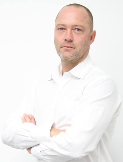 Man with short hair and in white shirt crosses arms and looks at camera....