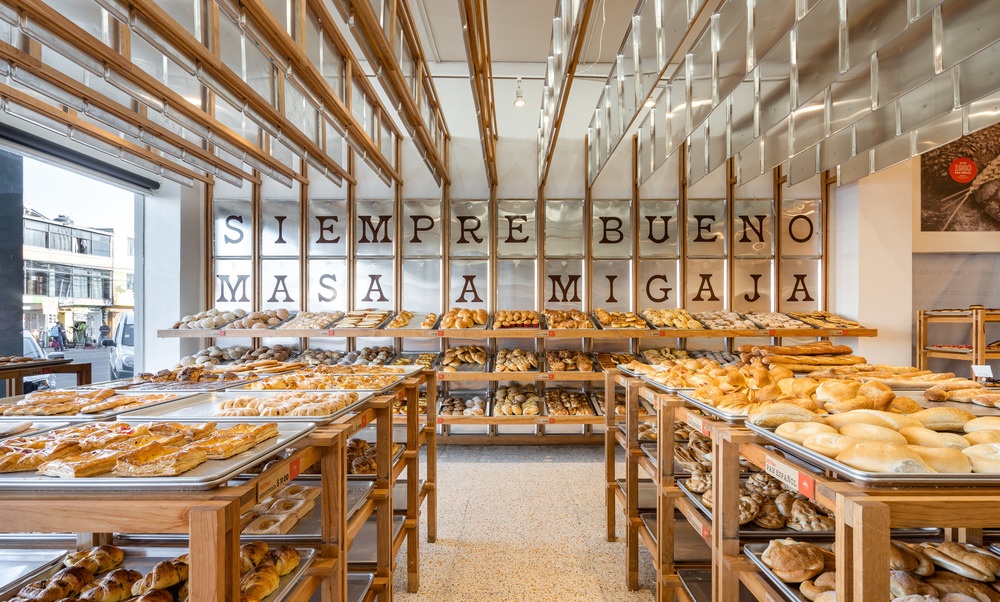 A counter display in a bakery with many different breads and buns...