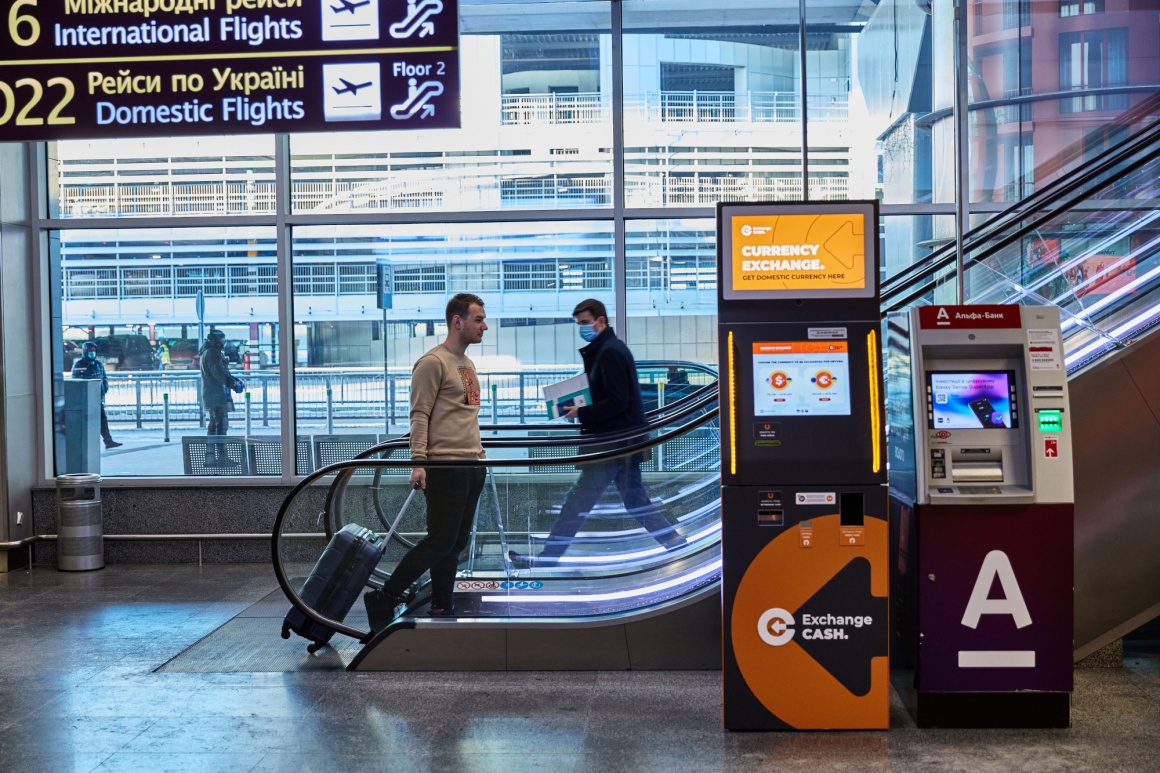 A currency exchange machine in front of an escalator...