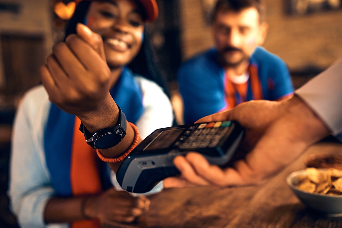 A person uses a smartwatch to pay at a card reader