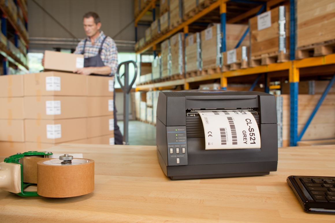A label printer stands on a table in a warehouse