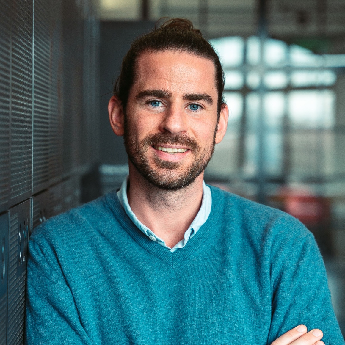 Young man with brown hair and brown beard in a turquoise pullover...