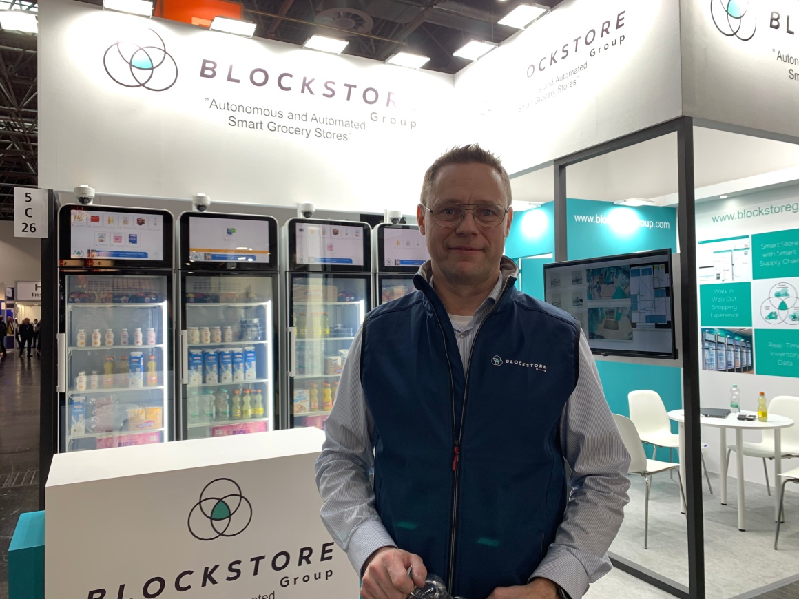 Man with blue waistcoat in front of several refrigerators...