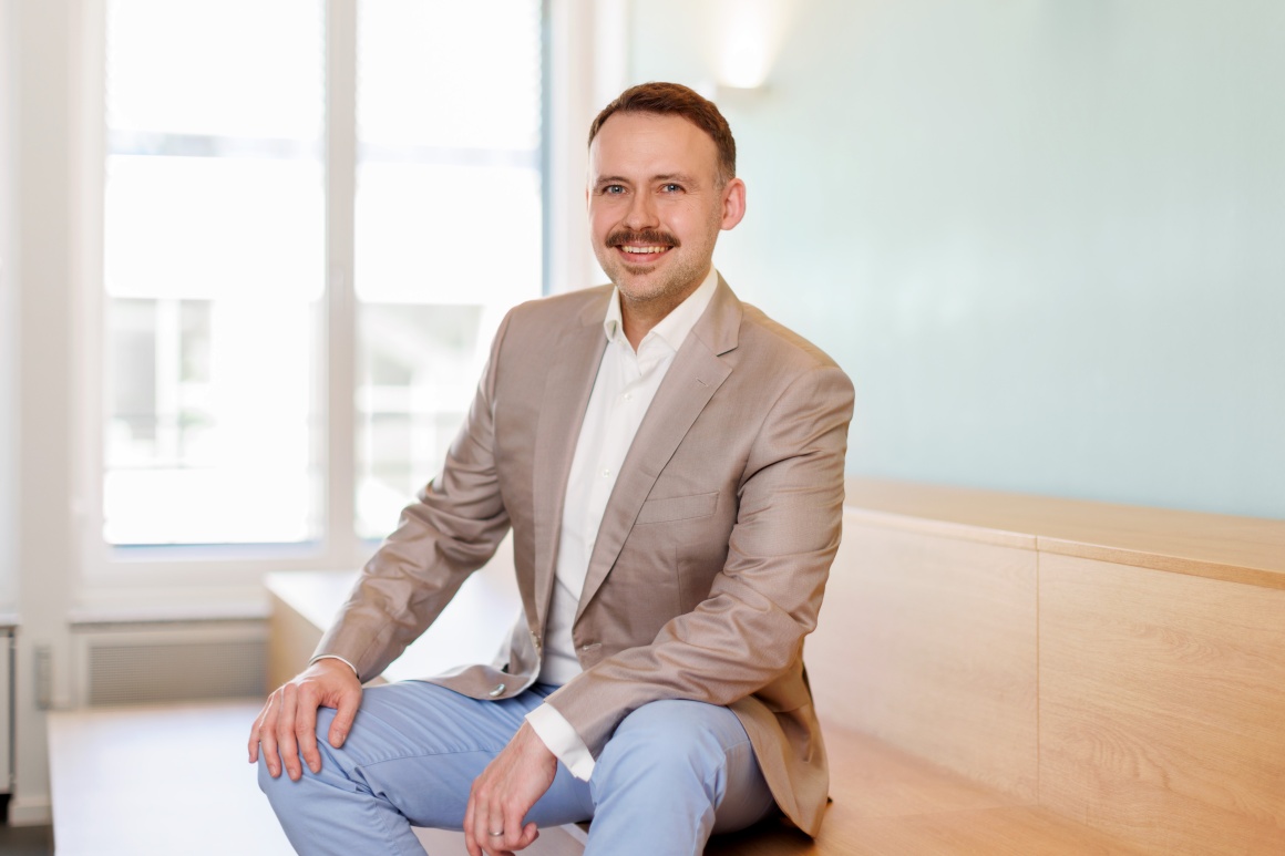 Fabian Mischler smiles into the camera while sitting....